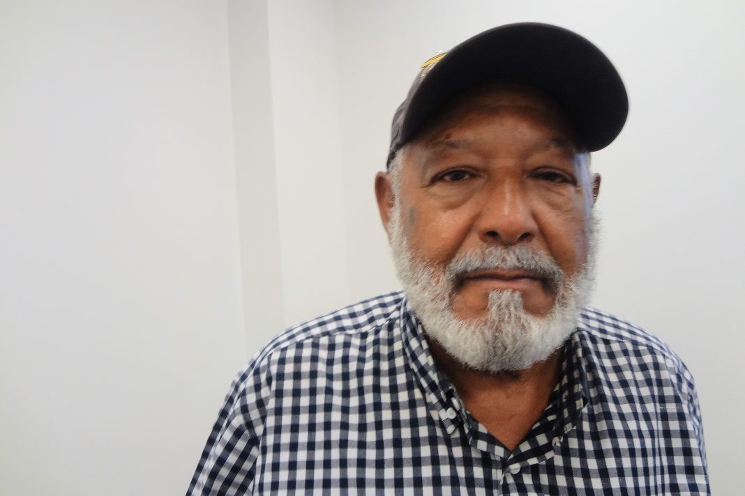 A photo of a Black man seated and facing the camera.